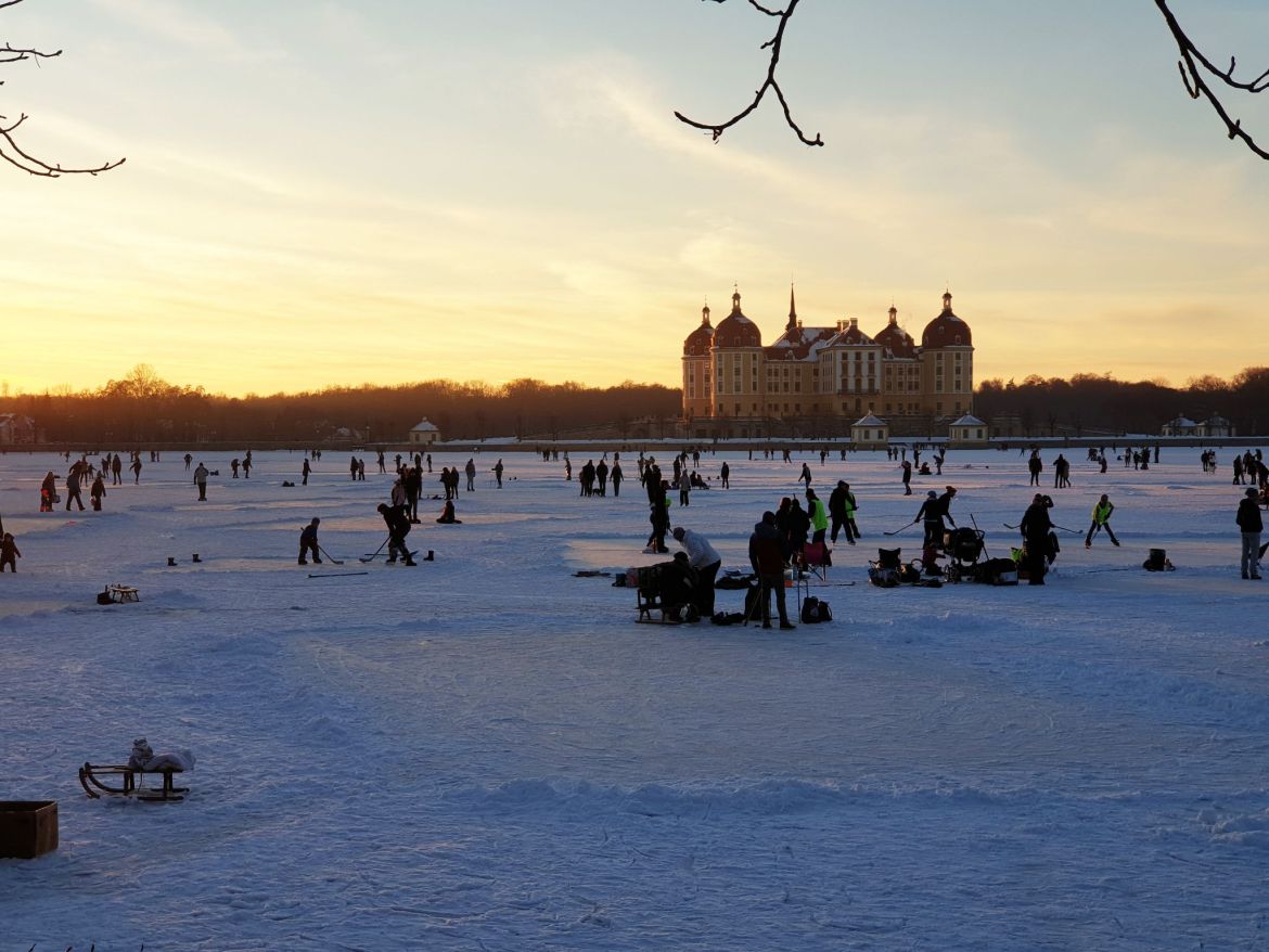 Menschen haben Spaß auf einem zugefrorenen See bei Moritzburg