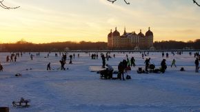 Menschen haben Spaß auf einem zugefrorenen See bei Moritzburg