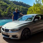 Robert hinter BMW 440i Coupé mit der Bucht von Cala Tuent im Hintergrund